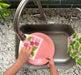 Beet sponge cloth being used to clean dishes in a sink