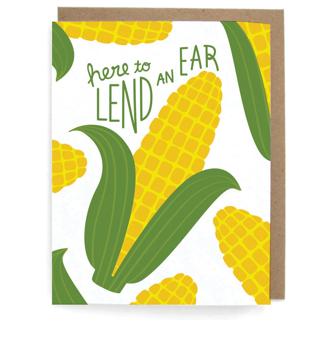 White card with corn design, featuring the phrase "Here to lend an ear," with a brown envelope