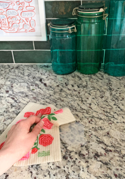 Roses sponge cloth being used to clean a spill on a counter