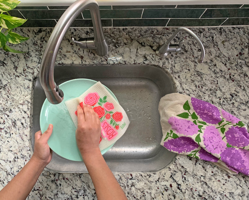 Roses sponge cloth being put under running water in a sink
